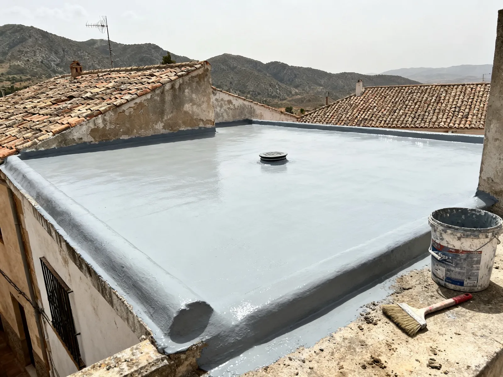 Cubierta plana de una casa de pueblo recién impermeabilizada con una capa gris continua